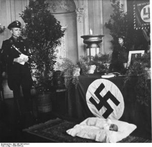 Sur cette photo, l'enfant baptisé est allongé devant un swastika.