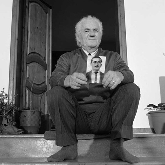 Photograph of Sazan Hoxha with photograph of his father, Nuro Hoxha.