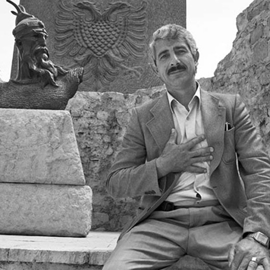 Photograph of Enver Alia Sheqer with statue of Albania's national hero, Skanderbeg.