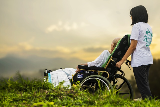 Hospice care client in wheelchair outdoors with caregiver