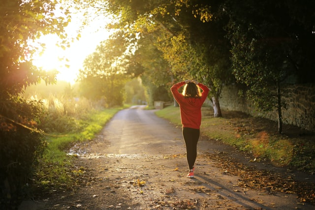 woman with her hands on her head walking into the sunset