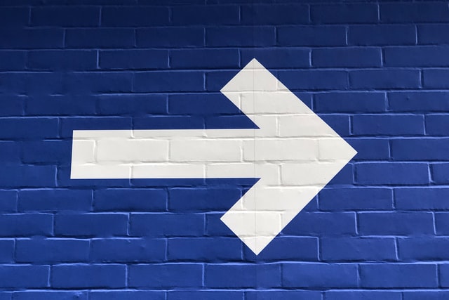 White arrow pointing to the right on a blue wall