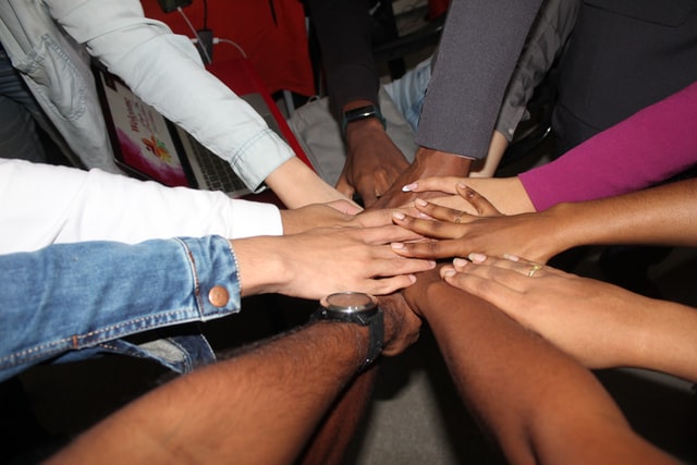 Hands of multiple genders and races touching in a circle