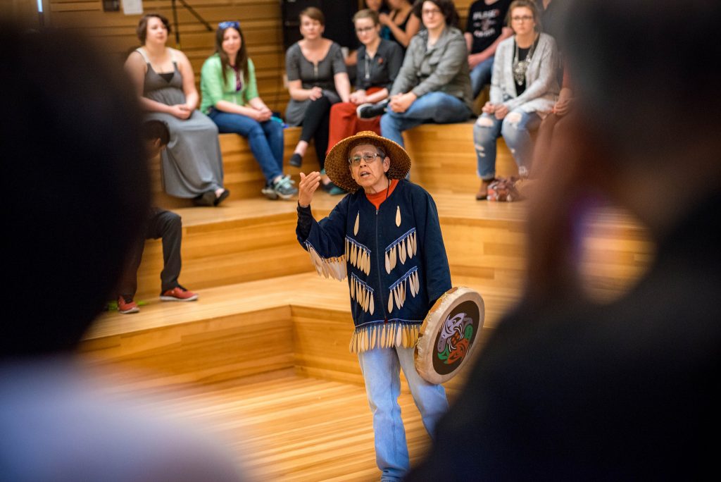 An indigenous man speaks to a crowd at an Indigenous Graduate reception.