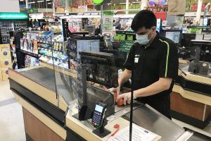 Grocery store employee scanning items at the cash register