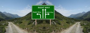 Two roads dissected by a hill and a sign pointing in four different directions, each labeled as the right way