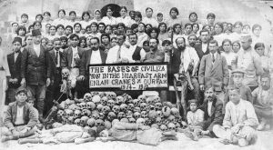 group of people standing behind a pile of skulls holding a sign in Romanian