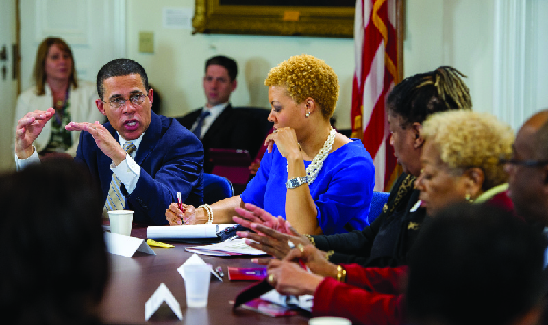 This image shows a group of men and women sitting around a table in discussion.