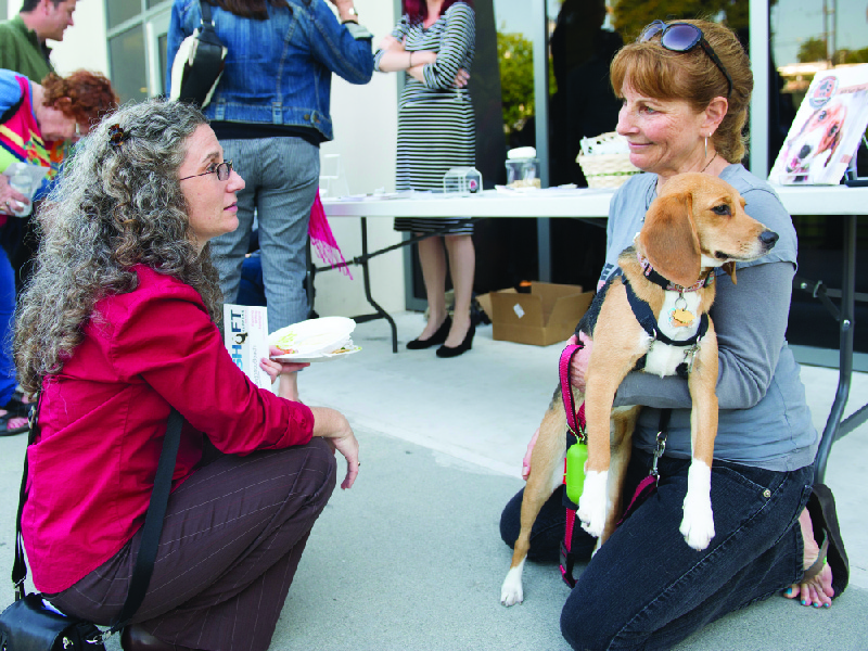 This image shows a person holding a dog and talking to another person.