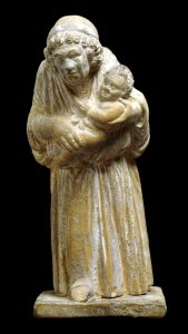 A yellowed terracotta figure of an old nurse holding a baby.