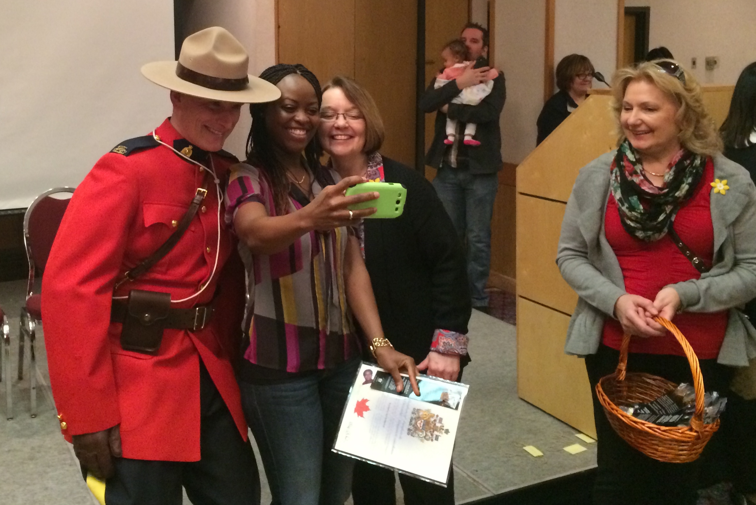 A woman takes a selfie with RCMP officer, others at her citizenship ceremony.
