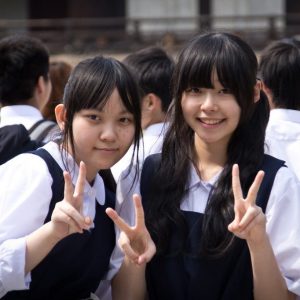 Two Asian people showing the peace sign with their fingers in public