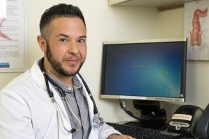A transmasculine doctor with his computer