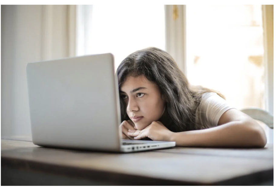 Female student slouched over the table looking at her laptop