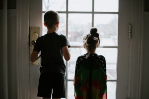 a boy and a girl looking out the window of a door