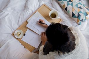 Person writing on a table on their bed.