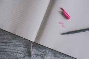 Notebook with pen laying open on a desk.