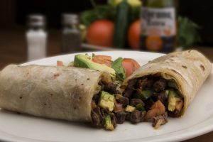 burrito cut in half on a plate with vegetables