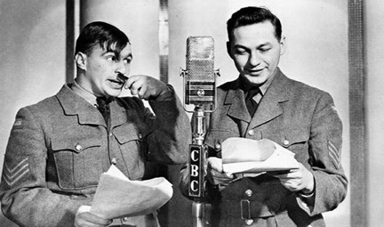 Wayne et Shuster, habillés en uniformes militaires, lisant un scénario et parlant dans un microphone de la CBC.