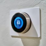 Digital thermostat on white wall.