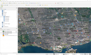 QGIS, with a shapefile representing historic monuments in Toronto, displayed as red dots over labelled satellite imagery.
