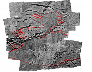 A mosaic of black and white aerial photos, showing areas of forest, water, and bare land. A red outline is draped over top of them indicating the modern boundaries of Dokis First Nation.