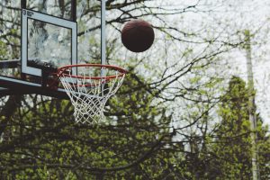 A basketball about to go through a basketball hoop.