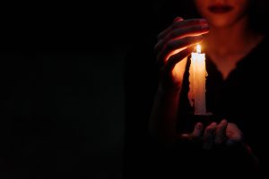 a person covering a lighted candle