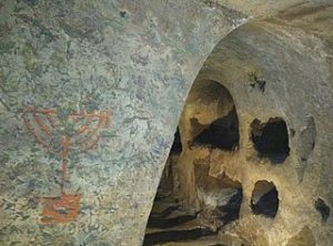 Jewish catacombs in Rome, with Menorah image on wall.
