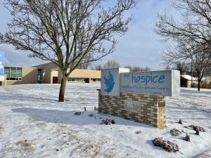 Outside the south entrance to the Hospice of Windsor and Essex County building with a sign on the front lawn