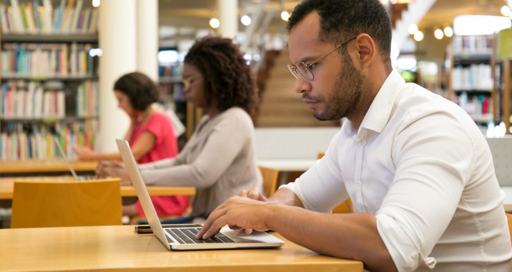 diversité raciale de stagiaires travaillant à l’ordinateur dans une bibliothèque publique