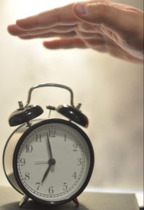 Photo of a person's hand reaching out to turn off a manual alarm clock