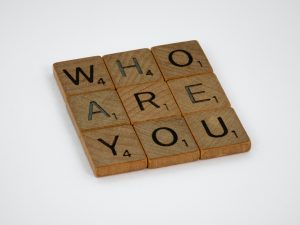 Scrabble tiles that spell out the question, "Who are you?"