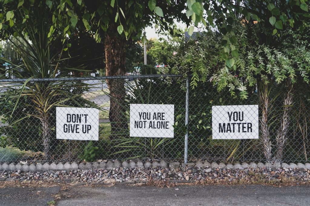 Fence with signs saying don't give up, you are not alone, you matter