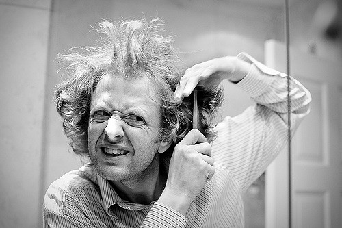 man looking in the mirror combing his messy hair