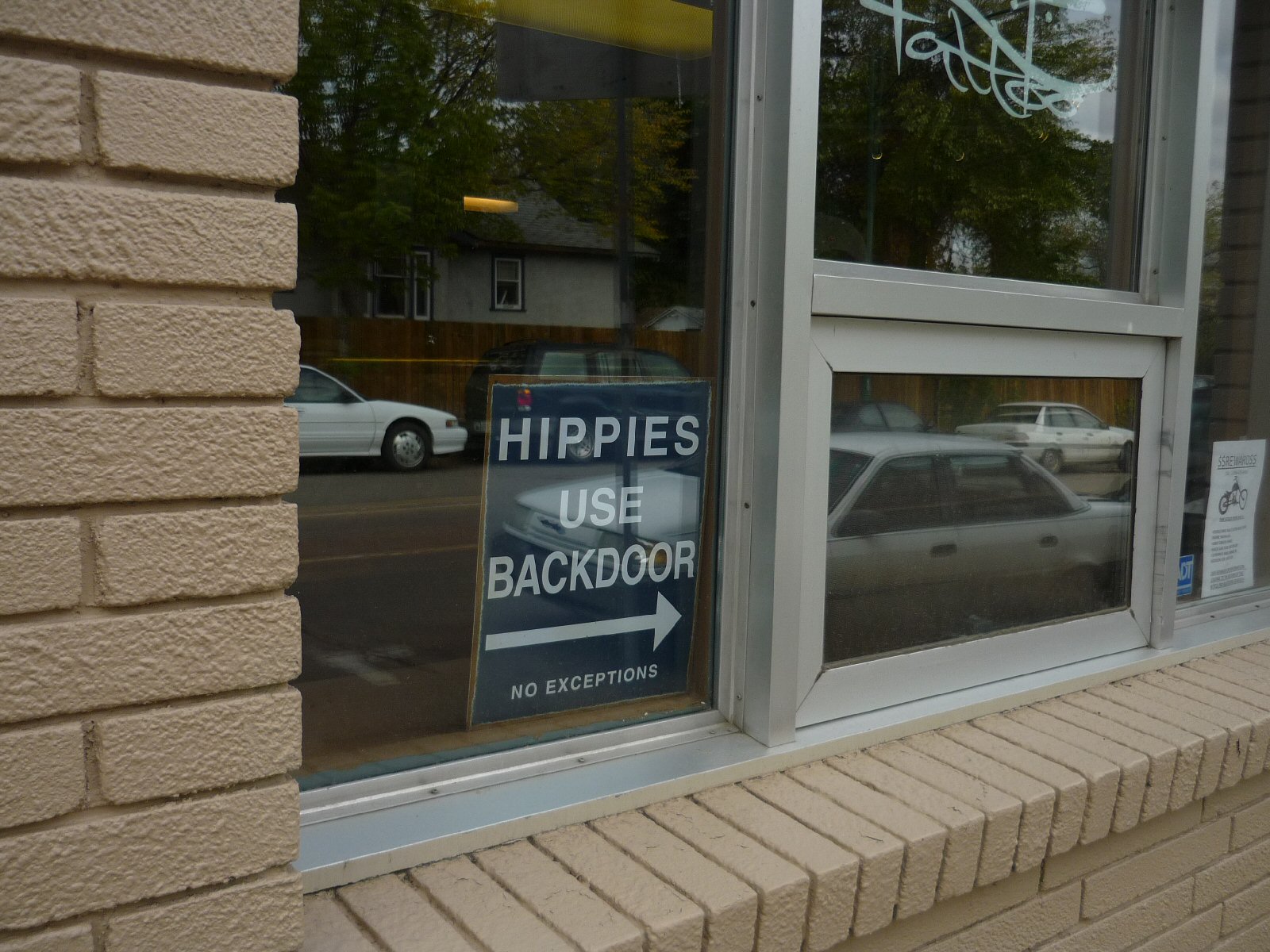 A sign saying "Hippies use Back Door" in the window of a shop.