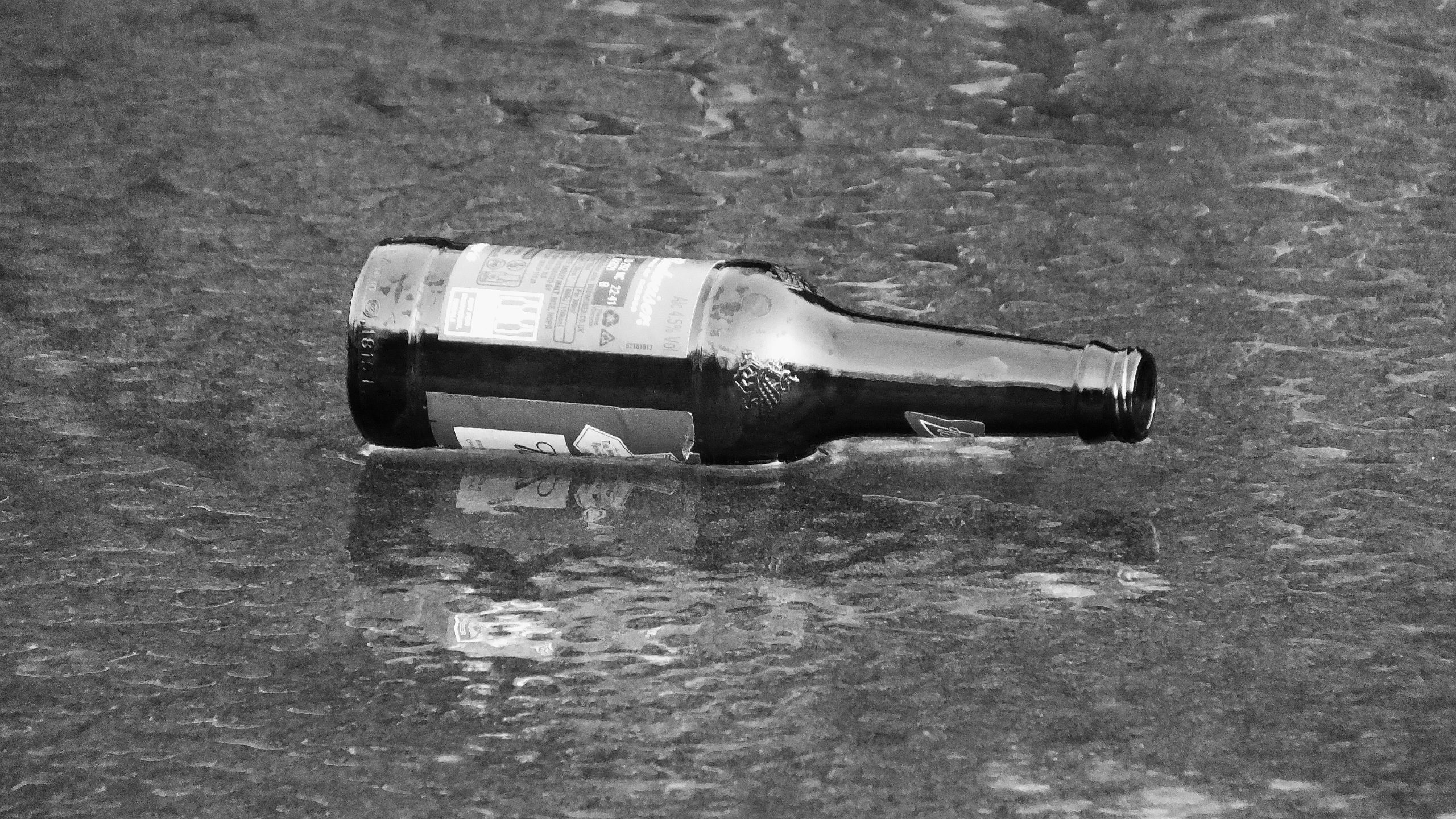 A beer bottle floating on a stream, hardly submerged at all.