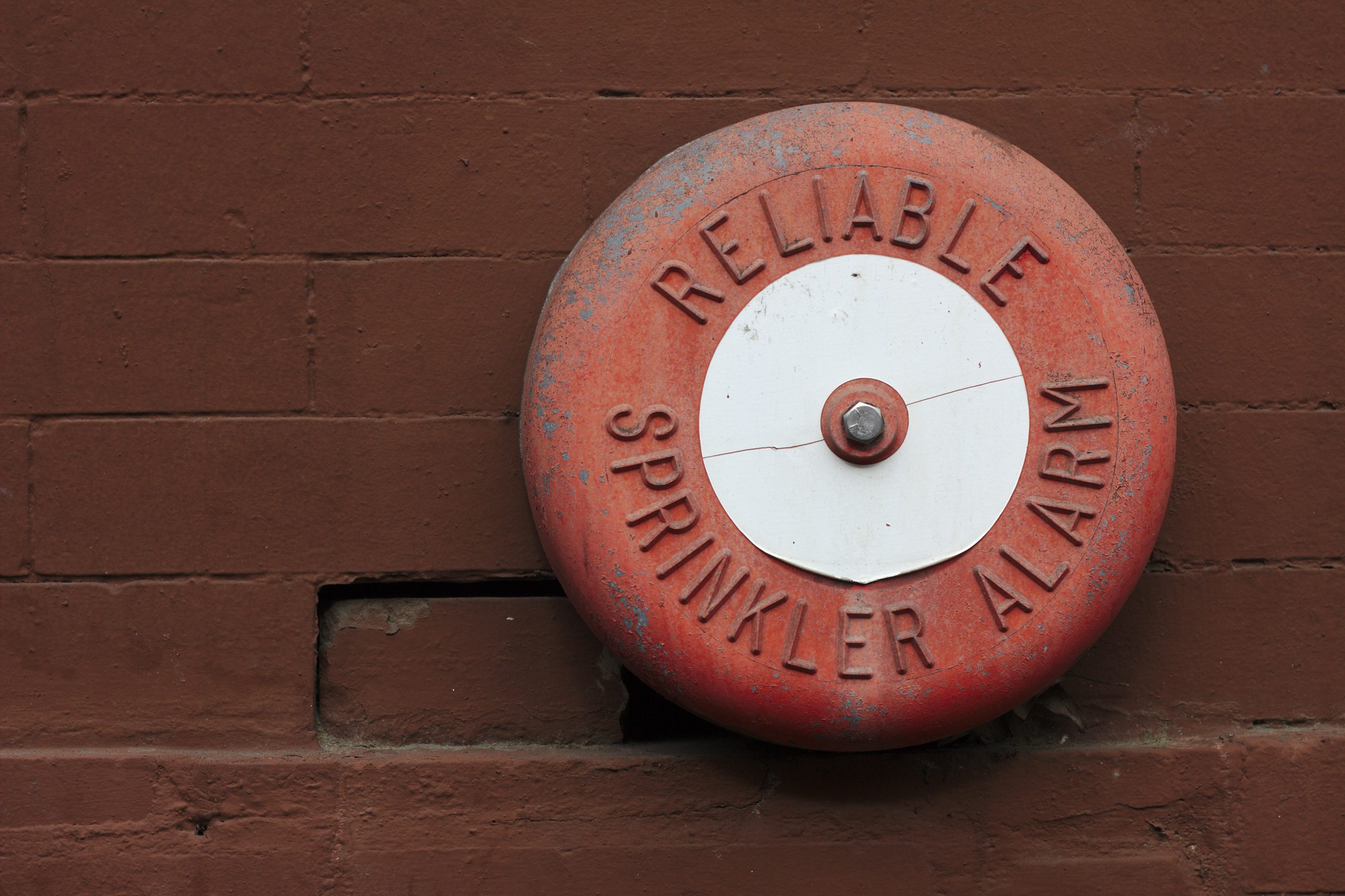 This image shows a round metal disk with the words "Reliable Sprinkler Alarm".