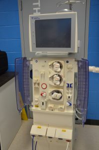 Photo of a dialysis machine (Fresenius) found in the Biomedical Engineering laboratory. Photo depicts the front view of the dialysis machine including monitor (top) and pumps/alarms (bottom, doors open).