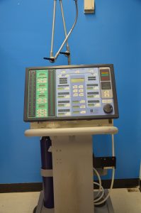 Alt text Photo of a ventilator found in the Biomedical Engineering laboratory. Photo depicts the front view of the ventilator with stand and oxygen tank.