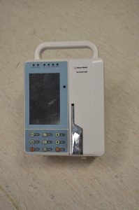 Photo of an Infusion Pump (Advance Medical) found in the Biomedical Engineering laboratory. The photo depicts the front view of an infusion pump with the door closed and locked.