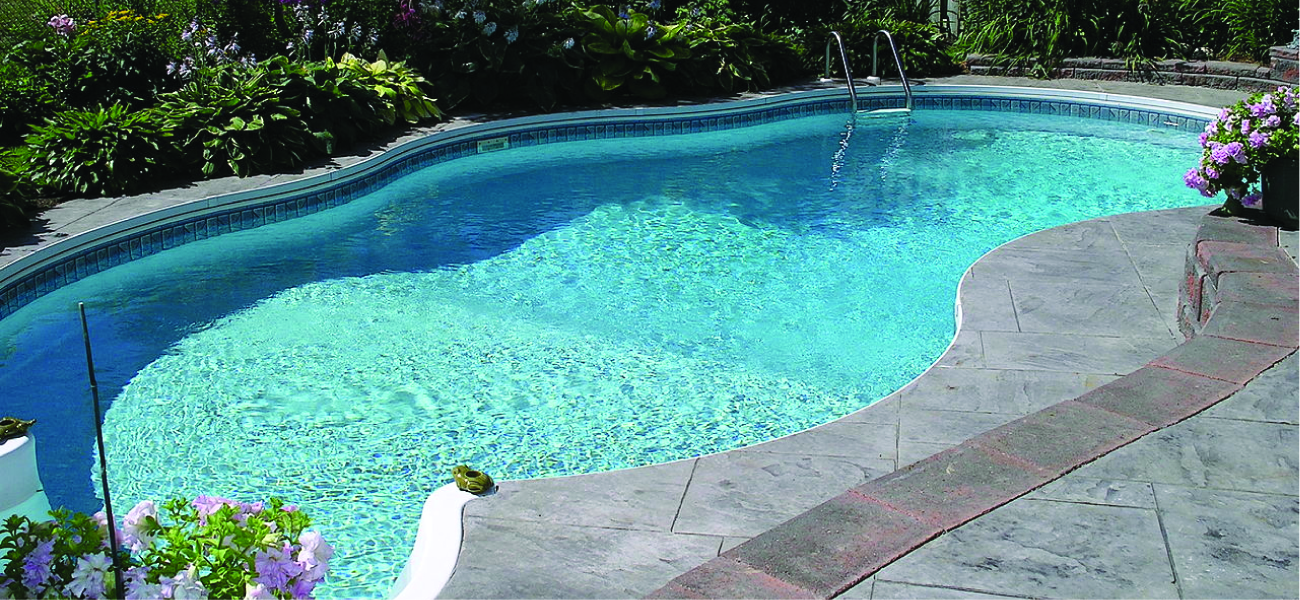 A swimming pool that is full of water and surrounded by a concrete patio is pictured.