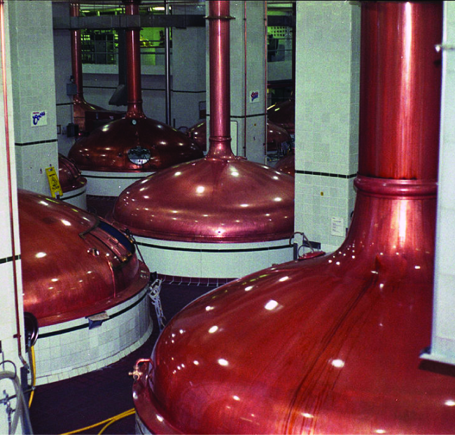 Four copper-colored industrial containers with a large pipe connecting to the top of each one are pictured.
