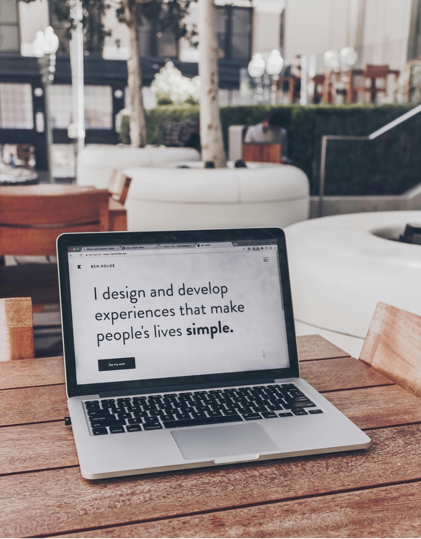 Photo of a laptop on a table with the words "I design and develop experiences that make people's lives simple."