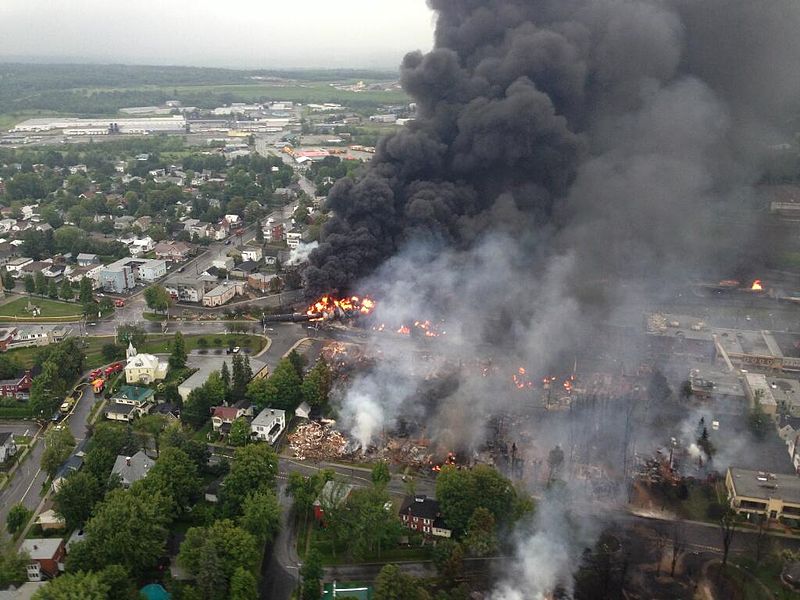 Bird's eye view of black smoke and a town on fire.