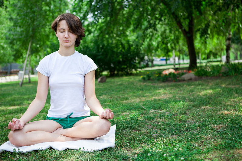 A woman meditates in a park.