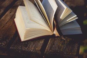 An open book laying on a picnic table.