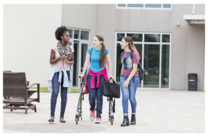 students walking on campus, including one student with a mobility aid