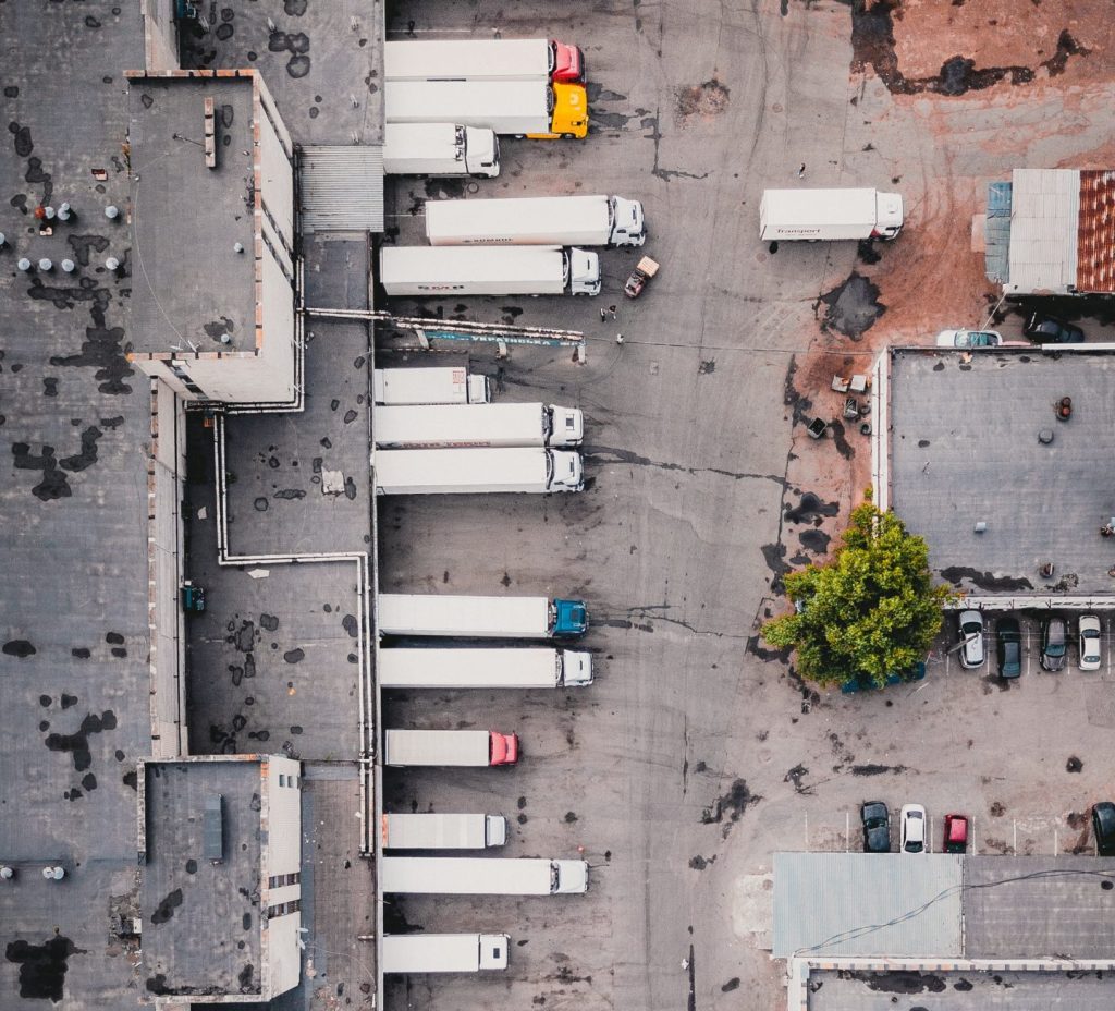 Drone overhead photo of a dozen large trucks being loaded at a warehouse