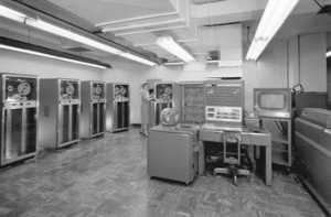 Black and white picture of a woman holding open the front panel of a Mainframe computer in a lab.